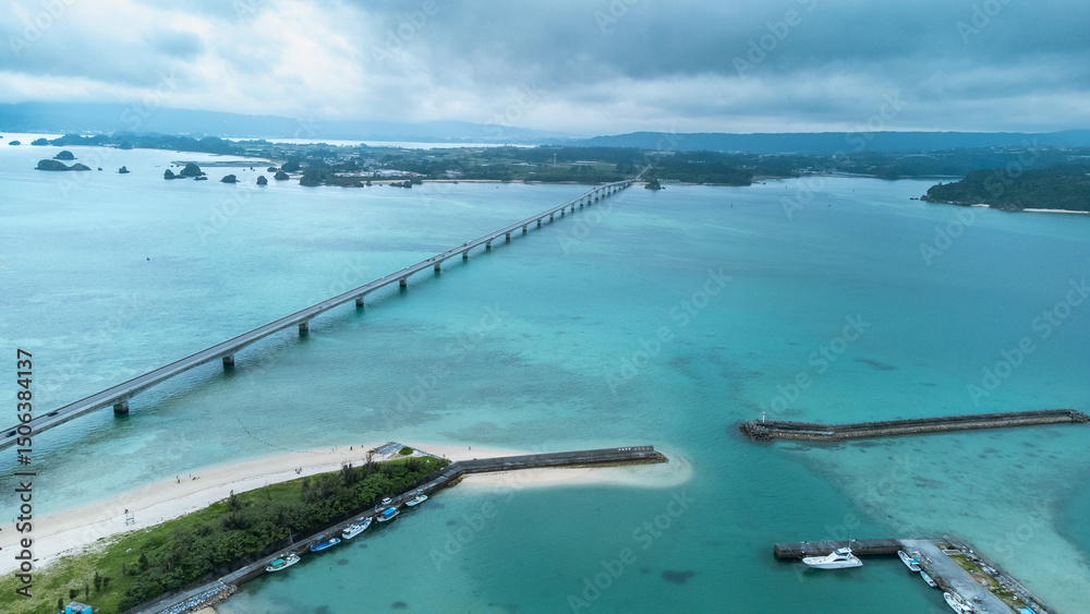 Obraz premium A Long bridge of Kouri Island and beach from a high view by drone with clear sky and sea water.