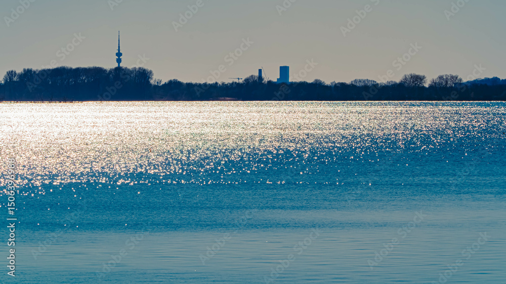 Fototapeta premium Spring landscape with the Olympia tower in the background on a sunny day at Ismaning Reservoir Lake, Munich, Bavaria, Germany