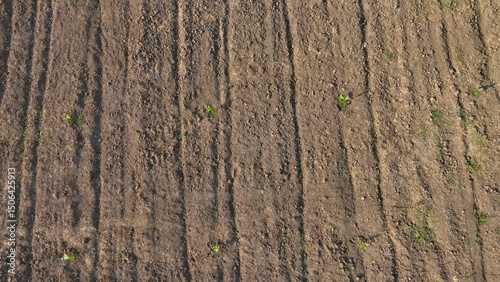An aerial view captures the freshly tilled earth, with its uneven texture and scattered straw, illustrating the field's readiness for planting new crops.
