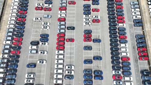 This bird's-eye view reveals the symmetrical layout of the parking lot, with orderly rows of cars and clearly marked spaces, creating a visual rhythm of organized vehicle storage.