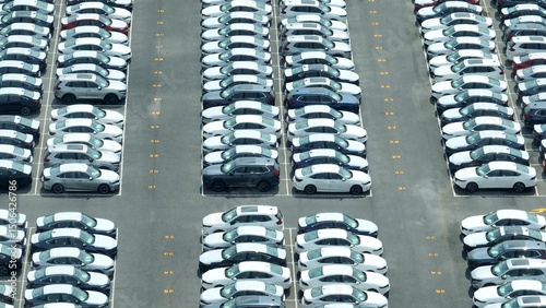 Fotografie This aerial perspective highlights rows of brand-new vehicles, each parked in neatly numbered spaces, symbolizing the automotive industry’s focus on inventory control and organized distribution