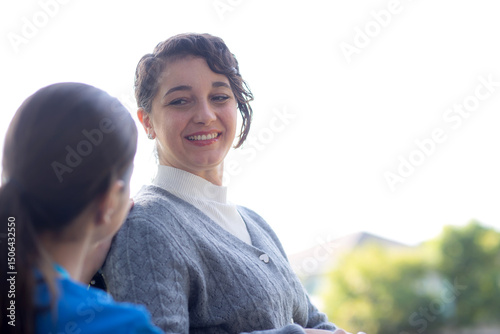 Young caucasian nurse comforting with patient while sitting on wheelchair in outdoor park, doctor woman support and counseling with patient, caregiver and service, medical and consoling.