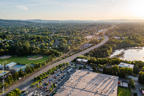 4K aerial photo of Tualatin Valley Highway in Beaverton, Oregon, heading west at sunset. Scenic view includes tennis courts, baseball fields, distant neighborhoods, and surrounding nature