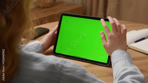 Woman sit desk use digital tech tablet with green screen mock up. Hand scroll pad web site, swiping like photos. Girl hold pad close up. Chroma key page. Cozy home background. Online app copy space.