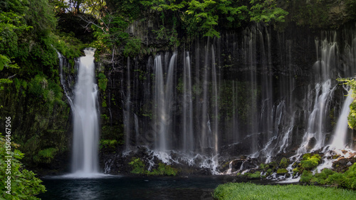 Breathtaking view of Shiraito no Taki waterfalls cascading down a lush, moss-covered cliff into a tranquil pool below. photo