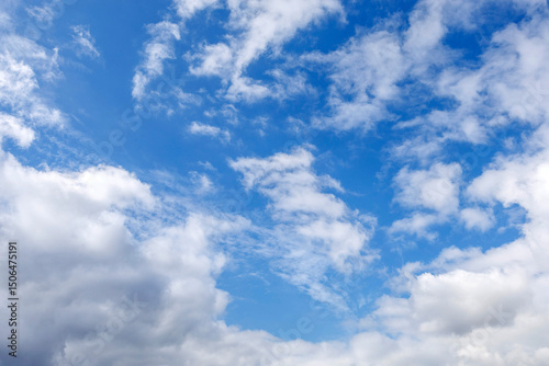 Dynamic cloudscape with soft white cumulus clouds drifting across a vivid blue sky, ideal as background or atmospheric element