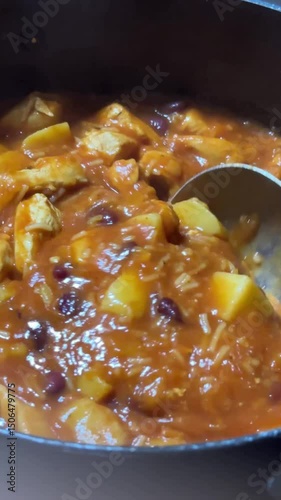 close up of stirring delicious hearty meal, slow cooked chicken stew made with potatoes and red beans