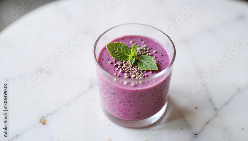 Purple smoothie with seeds and mint in a glass on marble table   photo