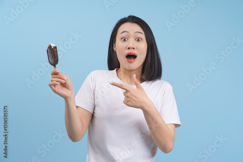 Excited woman holding a chocolate ice cream bar with a surprised expression in a studio