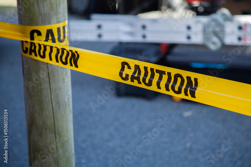 Caution tape around a post with ladder behind