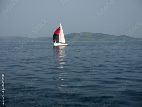 White sail yacht reflection in the sea 