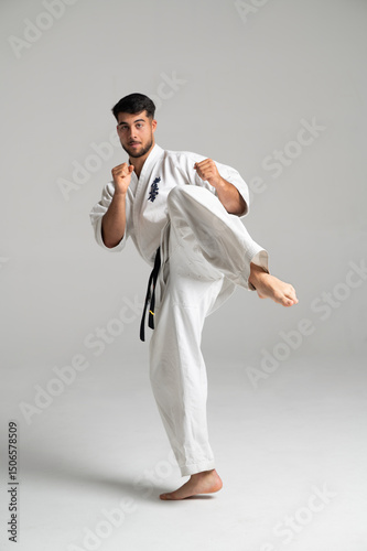 Kyokushinkai karate fighter kicking high in studio setting