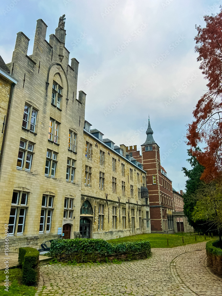 Obraz premium Linear facade of modern buildings in Leuven with tower and green surroundings