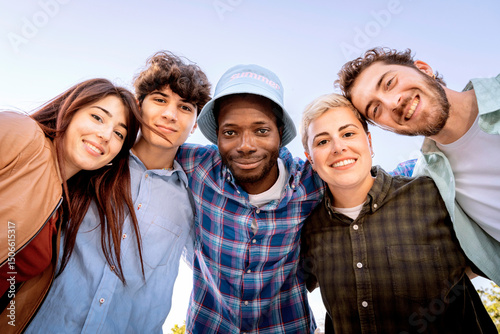 Happy group of young multiracial friends smiling and looking at camera outdoors