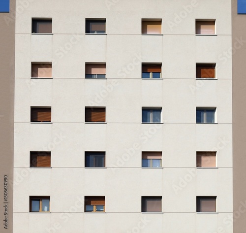 Off-white apartments building facade with open, half open or closed brown shutters. Background for copy space.