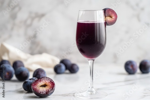 Dark purple plum juice in a stemmed glass with a plum slice garnish.