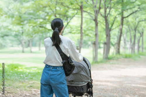 ベビーカーを押して公園を散歩する母親