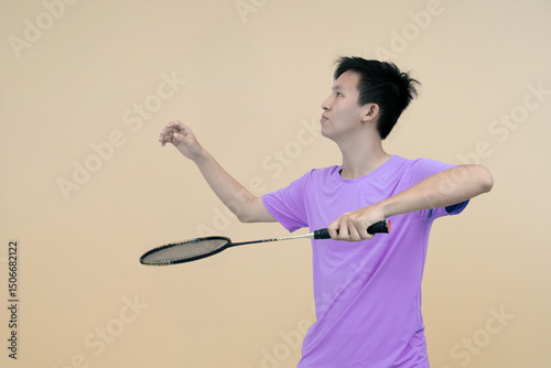 young man playing badminton doing service pose in isolated minimalistic background 