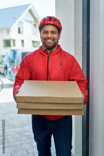 Smiling deliveryman holding pizza box while standing at doorway photo