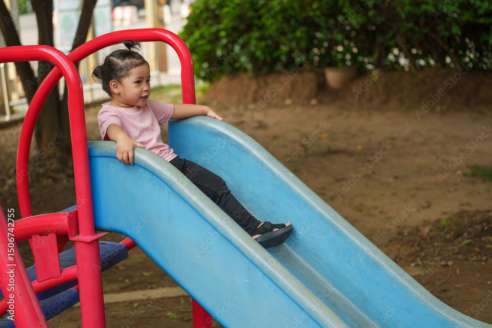 Naklejka premium happy toddler baby girl sliding and playing at playground