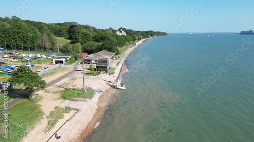 An aerial view captures the scenic beauty of Fishbourne Beach on the Isle of Wight, showcasing the sandy shore, clear blue waters, and lush greenery under a clear sky. photo
