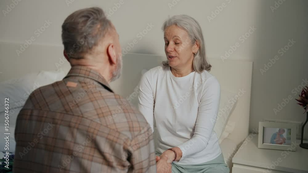 A woman sits on a bed and talks while stroking the head of a man sitting next to her, then they hold hands A woman sits on a bed and talks while stroking the head of a man sitting next to her, then they hold hands