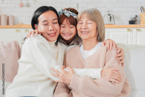 Asian multigenerational family grandmom mother and daughter nephew offspring and granddaughter smiling happily together at camera on sofa The love of a family makes life beautiful	