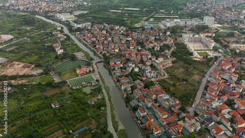 Top-down aerial view of a narrow canal winding through lush suburban housing, lined with tropical trees and adjacent garden plots