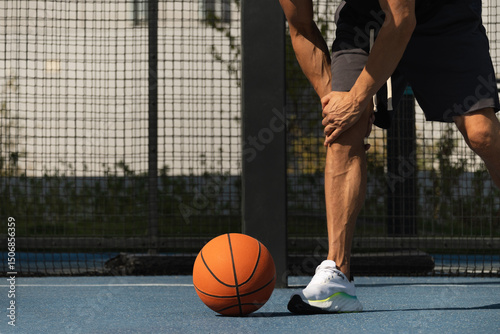 Basketball ankle injury or pain. Professional athlete or sportsman with accident. Basketball player check knee after sport workout. Close up.