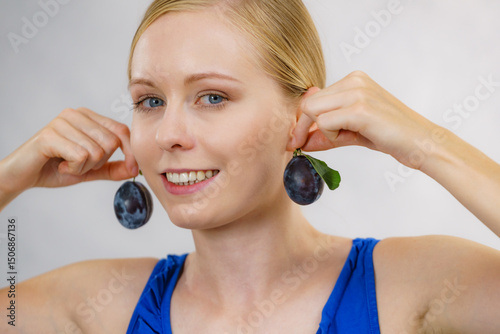Girl holds plum fruit to her ear