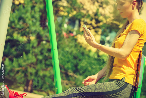 Girl doing exercises outdoor, holding phone