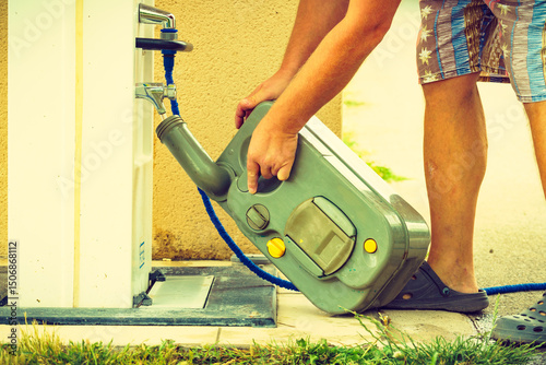 Man emptying caravan tank toilet cassette in dump station.