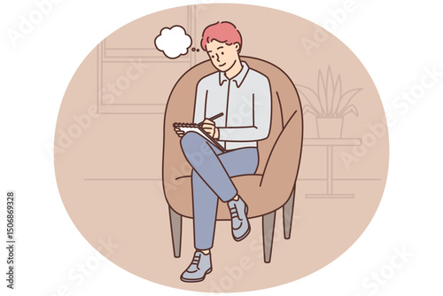 Adult man sits in cozy chair and makes notes in notebook making plans for day