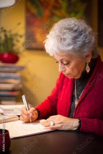 An elderly Hispanic woman writes personalized holiday cards to corporate partners. Her thoughtful tradition nurtures long-lasting business connections.