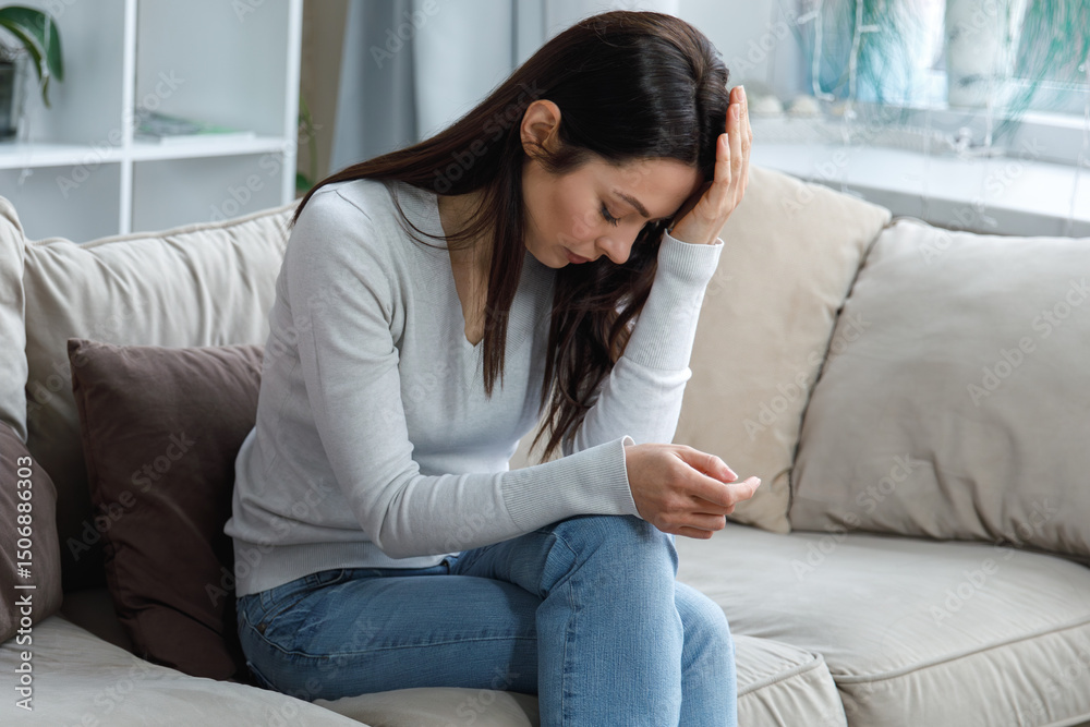 Fototapeta premium Young woman suffering from headache sitting on couch at home