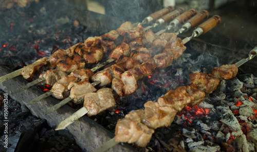 Grilling shashlik on metal skewers on grill, barbecue grill over charcoal
