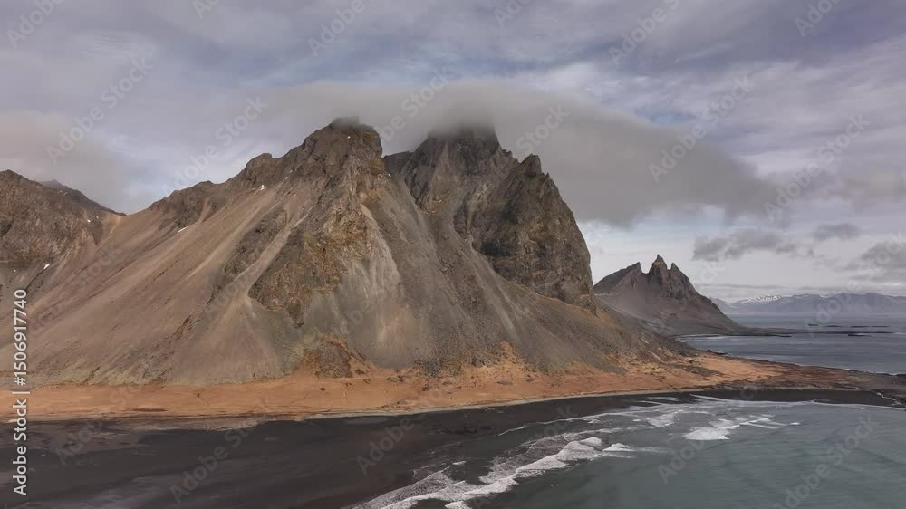 Vestrahorn and Brunnhorn rise over black beach and crashing waves on Iceland's Stokksnes peninsula. Stokksnes, Iceland