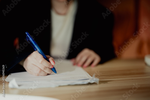 Close-up of a woman completing an HR form at her office desk. Suitable for recruitment or employee onboarding themes.