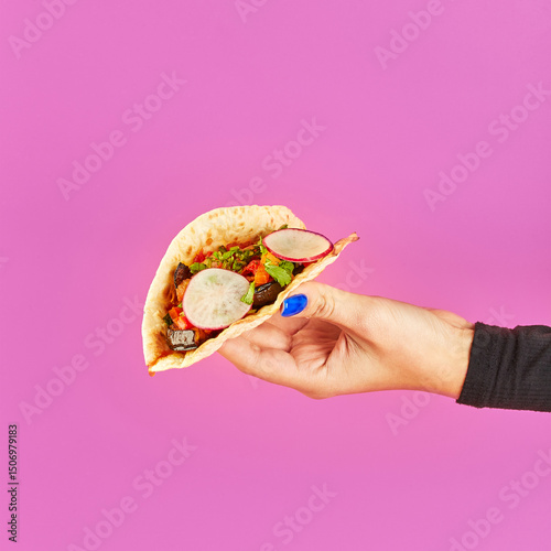 Taco on corn tortillas with beef, chicken and vegetable fillings in woman's hand on lilac background