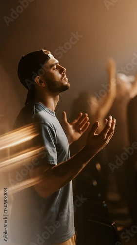 Emotional moment during a worship session where a young man connects deeply with his faith in a dimly lit space