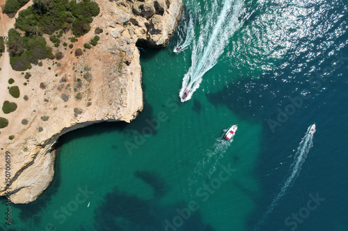 Motor boats pass below near the seven hanging valleys trail in Algarve, Portugal