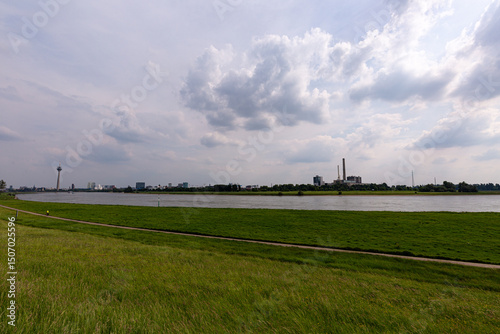 Grass field, Rhine river and Dusseldorf in the distance with cloudy sky