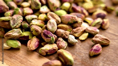 Peeled roasted pistachio kernels scattered on wooden table. Macro shot. Rotation