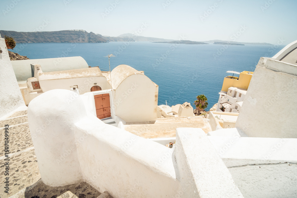 Fototapeta premium numerous houses and fences on the cliff of Santorini island. Oia village in the foreground and Cyclades islands in the background.