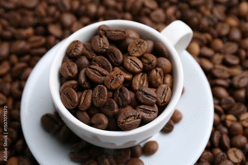 Fototapeta premium Cup and saucer on coffee beans, above view