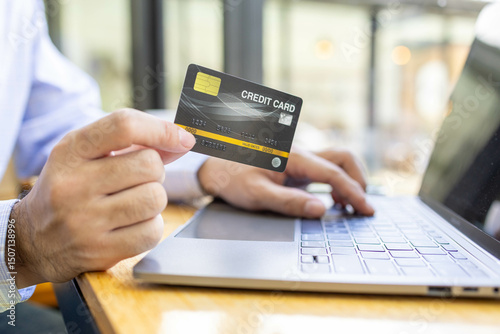 A man is using a laptop to pay for something with a credit card. Concept of convenience and ease, as the man is able to complete his transaction quickly and easily using his laptop
