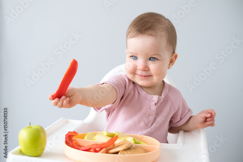 cute baby eating solid food sitting in a baby chair. weaning