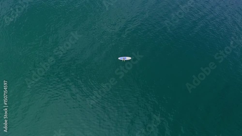 Top view surfer lying at turquoise sea water enjoying summer hobby. Stormy wave covering unrecognizable sporty person making white foam in super slow motion.