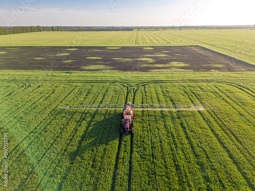 Modern Tractor Spraying Crops in Lush Green Field. Aerial front view view 