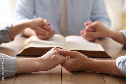 Foto Family with Bible praying at wooden table indoors, closeup